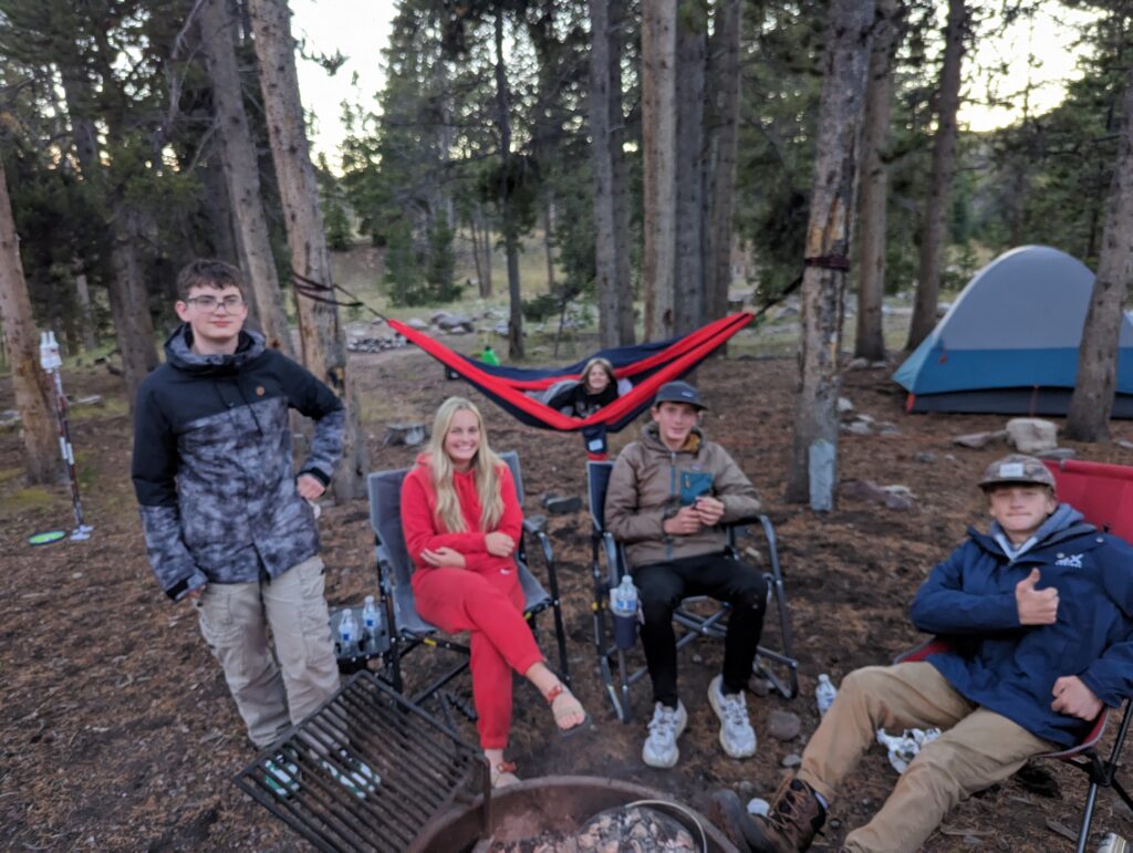 kids in camping chairs hanging around a camp fire