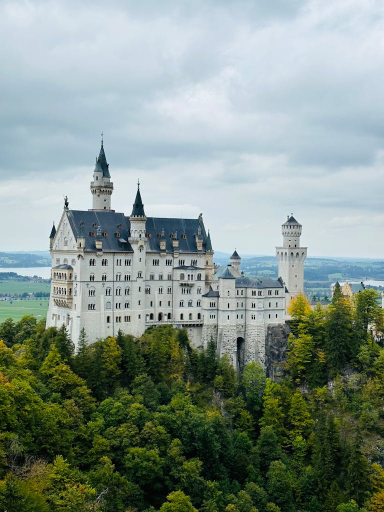 Aerial view of Neuschwanstein Castle surrounded by lush greenery and forest in Bavaria, Germany.