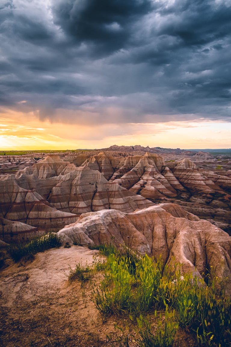 Explore the stunning rock formations of the Badlands under dramatic skies at sunset.